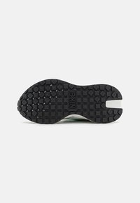 Suela de zapato de goma negra con superficie texturizada, que presenta patrones de diamante en relieve y un logotipo de Nike en el centro. Forma curva en la punta.