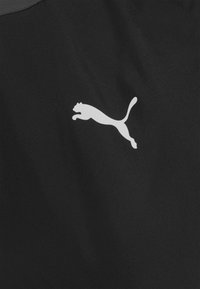 Zwarte atletische stof met een wit Puma-logo in de vorm van een springende kat, gladde textuur met een lichte glans.