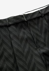 Tissu noir avec un motif en chevrons, featuring des rayures subtiles. La ceinture a un design plié avec un petit fermoir en argent.