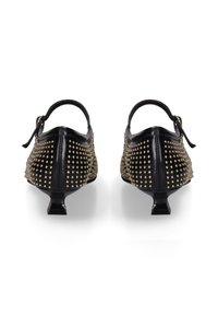 Zwarte leren schoenen met een spitse neus en een lage hak, voorzien van gouden studs die in een patroon over de zijkanten zijn geordend en een achterkantriem.
