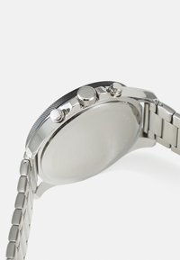Edelstahlarmbanduhr mit rundem Gehäuse, strukturiertem schwarzen Lünette, zwei Druckknöpfen und einem silbernen Metallarmband mit glatter Oberfläche.