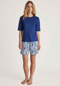 Blue cotton T-shirt with short sleeves paired with white shorts featuring a blue floral pattern. The outfit is casual and relaxed fit.