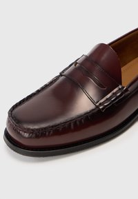 Burgundia nahast loafers, millel on õmmeldud detailid, ümar varvas ja dekoratiivsed esivedrud. Sile tekstuur ja madal konts.