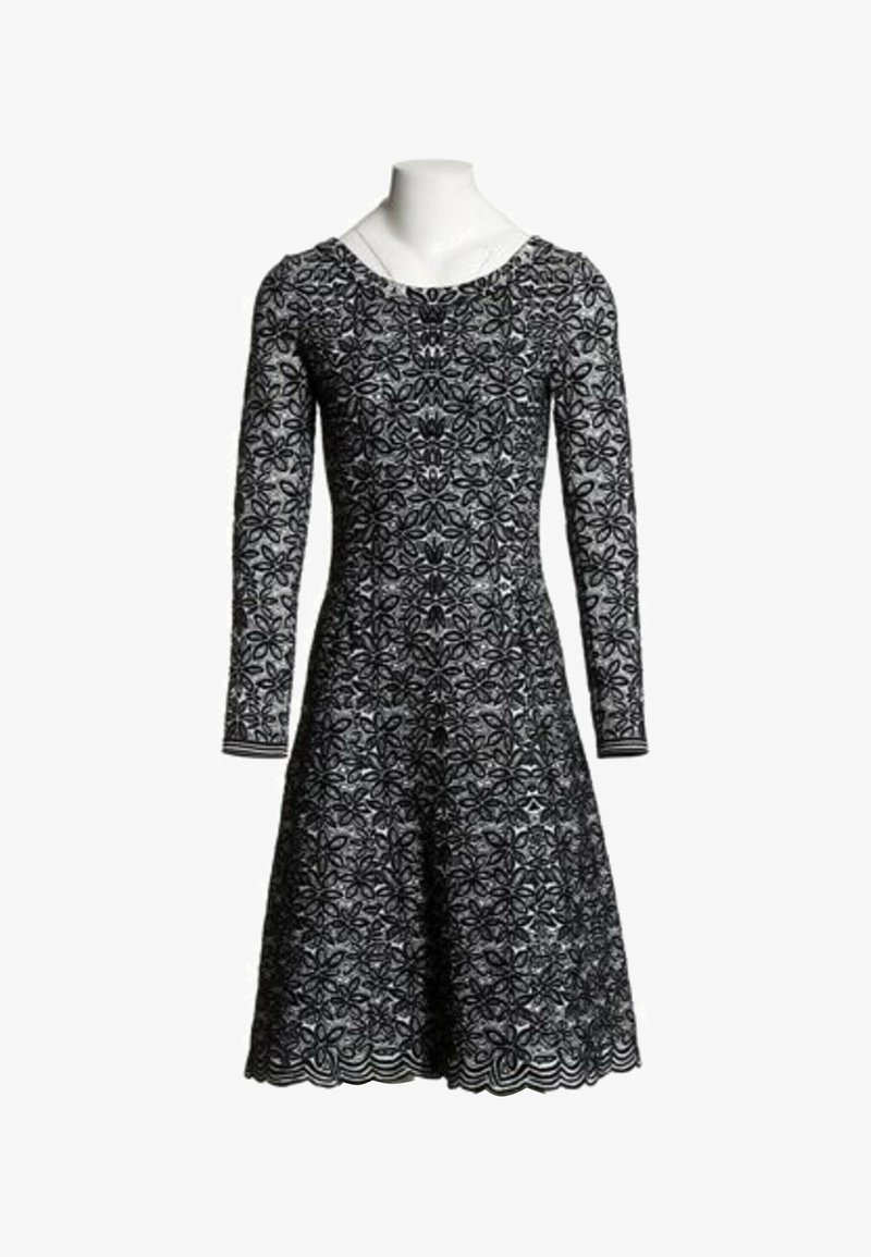 Robe en dentelle noire avec manches longues et motif floral, corsage ajusté et jupe évasée présentée sur un buste de mannequin blanc.