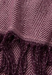 Textured woven throw with a herringbone pattern, featuring a dark purple and mauve color scheme, finished with long, decorative fringes.