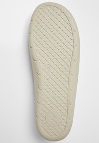 Semelle de chaussure en caoutchouc beige avec motif de bande de roulement en forme de losange, marquage taille 42, et logo circulaire près du talon sur fond blanc.