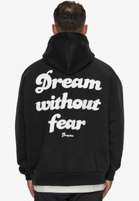 Hoodie noir avec un grand design en texte blanc au dos indiquant "Rêve sans peur" et le logo "Dropsize", comprenant une capuche avec cordon.