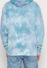 Blue tie-dye hoodie with a soft texture, featuring a hood and ribbed cuffs, designed with varying shades of blue and purple.
