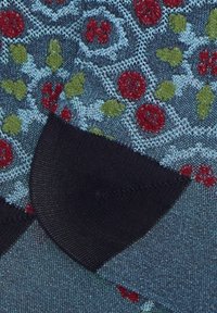 Tessuto a fantasia floreale con disegni rossi e verdi su uno sfondo blu scuro. Bordo nero lungo i lati. Texture morbida.