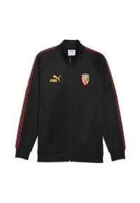 Sort atletisk jakke med høj krave, lynlås foran, røde mønstrede sidepaneler, gult "KING" logo og klubemblem på brystet. Blødt materiale.