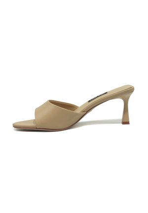 Beige mule med åben tå, lavt, buet stilettohæl og en glat læderoverdel på hvid baggrund.