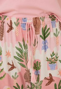Pantaloni corti in cotone leggero con uno sfondo rosa, caratterizzati da un motivo di piante e uccelli, fascia elasticizzata in vita con cordoncino e nappine.