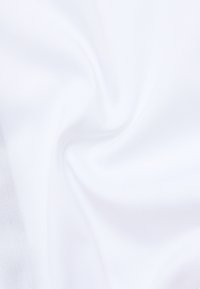 Tessuto bianco con una superficie liscia, caratterizzato da una leggera lucentezza e una lieve elasticità, disposto in morbide pieghe.