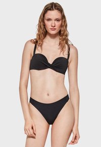 Bikini negro con un diseño retorcido en la parte superior, tirantes finos y parte inferior de tiro bajo a juego, fabricado en un tejido suave.
