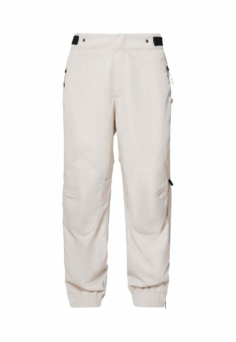 Helle beige Cargo-Hosen aus strapazierfähigem Material. Mit verstärkten Kniepatches, elastischen Bündchen und mehreren Taschen mit schwarzen Akzenten.