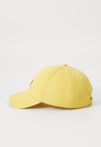 Sapca de baseball galbenă cu bor murat, confecționată din țesătură de bumbac. Include orificii de ventilație și un mic logo în față. Curea ajustabilă în spate.