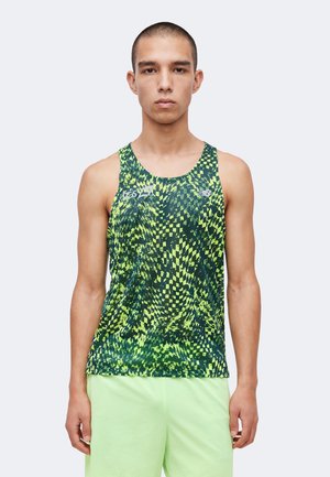 Jeune homme debout face à l'avant, portant un haut de sport sans manches à motif vert et jaune et un short vert clair.