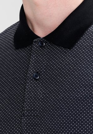 Czarna koszulka polo z fakturowanym wzorem, z czarnym kołnierzykiem, trzema guzikami oraz kontrastującym, małym białym wzorem.