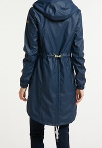 Námořnická modrá pláštěnka s kapucí, elastickým stahováním v pase a nabíranými manžetami; hladký, voděodolný materiál; bílé a žluté akcenty na hardwaru.