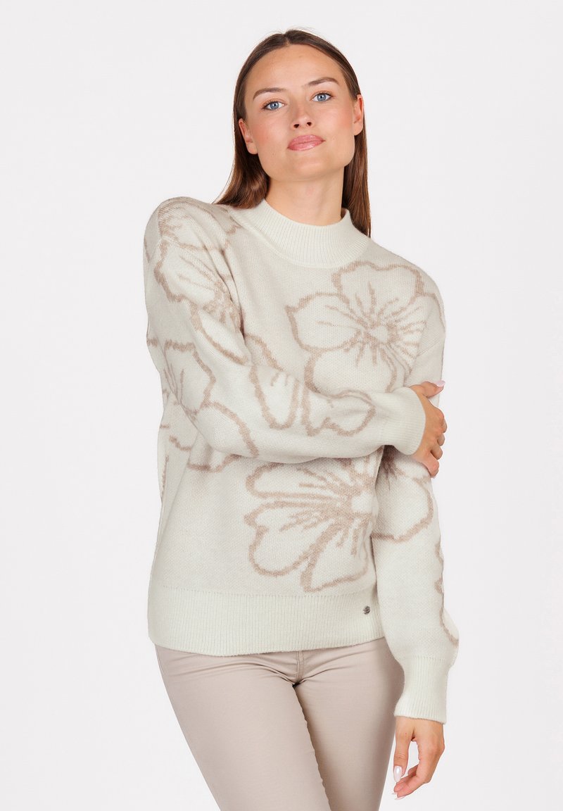 Pull en tricot de couleur crème clair avec un grand motif floral beige. Il présente un col rond et des poignets côtelés, avec une texture lisse et douce.