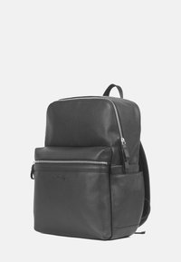 Svart läderryggsäck med en strukturerad design, dubbla dragkedjefack, framficka och justerbara axelremmar för mångsidighet.