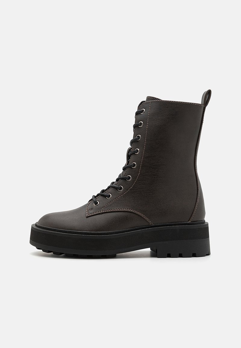 Bottines à lacets marron foncé avec une tige en simili cuir lisse, bout rond, semelle en caoutchouc noir chunky et détails de couture diagonale.