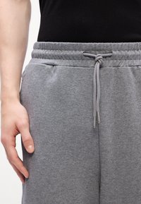 Gray sweatpants made of soft material with an elastic waistband, drawstring detail, and side pockets, offering a relaxed fit.