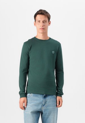 Long-sleeve green shirt made of cotton, featuring a round neckline and a small logo on the chest, paired with light blue jeans.