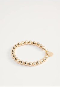 Zlatý náramok s pružinou s okrúhlymi korálkami a malým okrúhlym príveskom s vyrytými iniciálami na bielom pozadí.