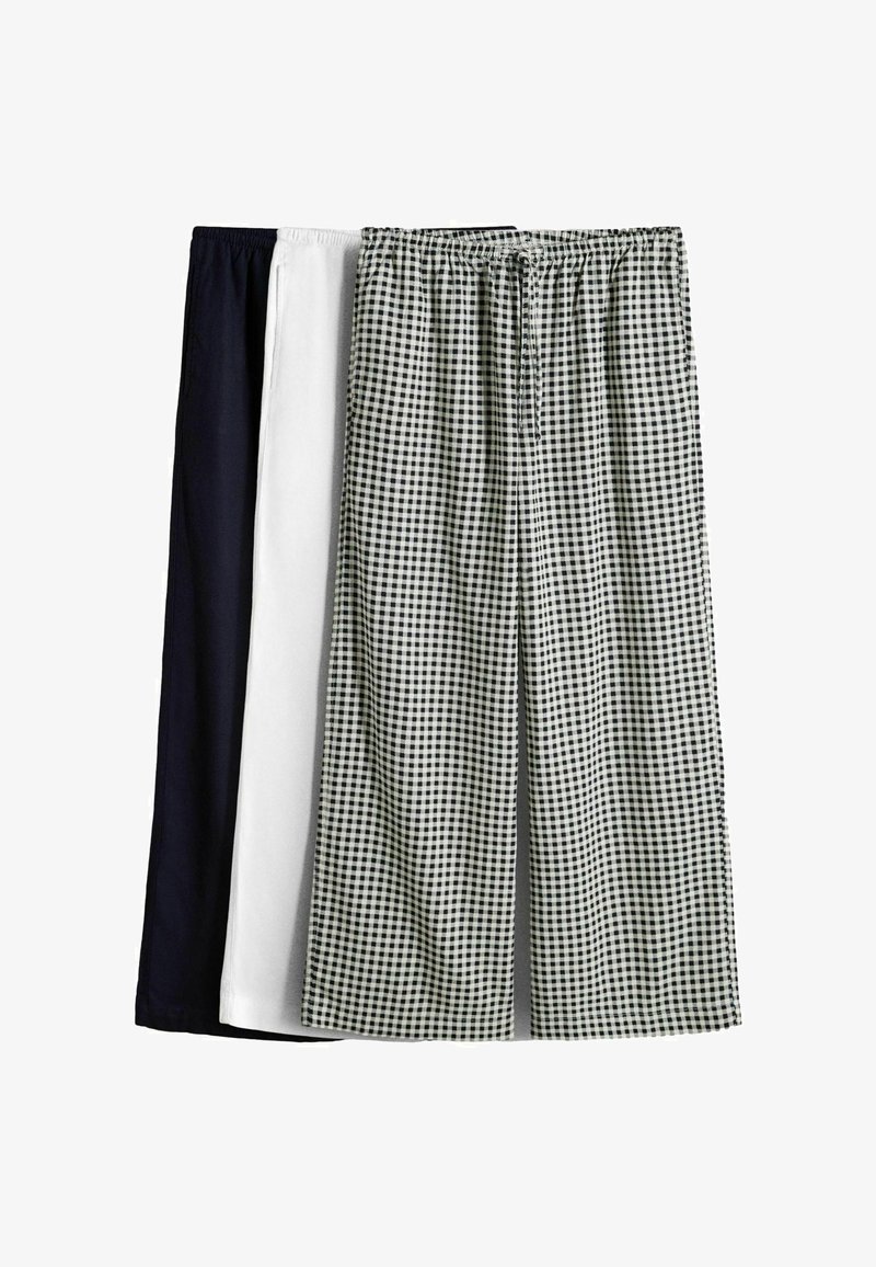 Drie paar loungebroeken met elastische taille en trekkoord, in zwart, wit en zwart-wit geruit patroon, naast elkaar weergegeven.