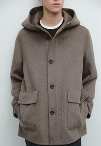 Cappotto marrone in misto lana con cappuccio, dotato di due tasche frontali, bottoni neri e una texture morbida. Semplice, dal taglio dritto con un design casual.