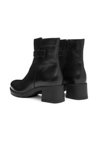 Bottines en cuir noir avec un bout arrondi, une fermeture éclair latérale et un accent en boucle. Présente un talon bloc épais pour plus de stabilité.