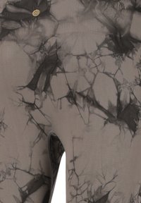 Leggings grises con un patrón negro y gris similar al mármol, textura suave y un detalle de abertura en el lateral. Incluye acentos en dorado.
