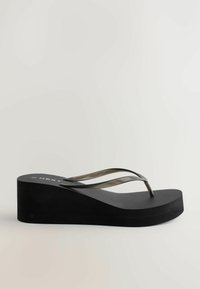 Sort platform-flipflop-sandal med transparente sorte remme og tyk sål, vist i sideprofil på en neutral baggrund.