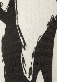 Black and white graphic textile featuring a bold abstract design on a cream background, showcasing a soft, textured knit material.