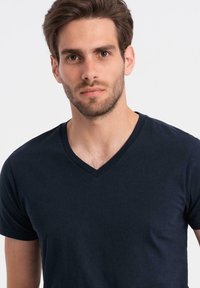 Námořnická modrá v-neck tričko z měkké bavlny, krátké rukávy, hladká textura, přiléhavý design s minimem švů.