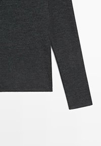 Šedý top s dlouhými rukávy z měkkého, texturovaného úpletu. Má rovný lem a boční rozparky pro snadný pohyb. Jednoduchý design.