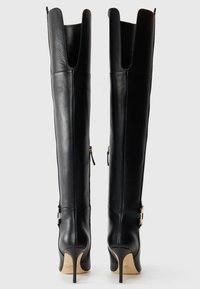 Black leather over-the-knee boots with a pointed toe, stiletto heel, side zippers, and gold hardware accents on the ankle straps.