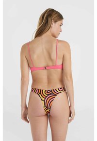 Roze bikini top met dunne banden en sluiting op de rug; hoog-geknoopte bottom met een levendig oranje en zwart draaipatroon.