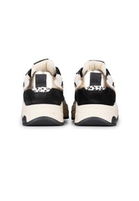 Sneaker in bianco e nero con una combinazione di materiali lisci e testurizzati. Presenta dettagli metallici dorati e un audace occhiello posteriore nero.