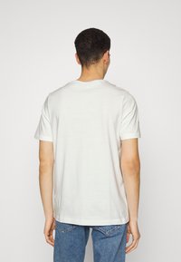 Hvid bomulds t-shirt med rund hals, korte ærmer og et enkelt design. Stoffet virker blødt med en afslappet pasform.