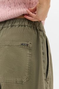 Pantalones verde oliva con cinturilla elástica, que cuentan con un bolsillo lateral y un parche cosido con el logo "BDG" en la parte posterior.