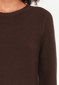 Dunkelbrauner, gerippter Pullover mit Rundhalsausschnitt, glatter Textur und langen Ärmeln. Hat feine horizontale Linien im Stoff.