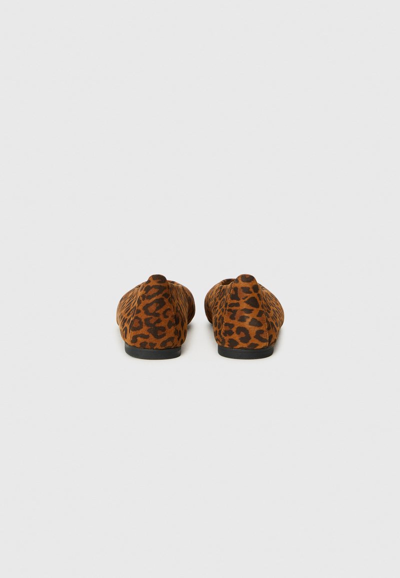 Mocasines de leopardo marrón con un acabado suave, punta redondeada y una suela baja de goma negra. El diseño es sin costuras y tiene un aspecto ajustado.