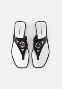 Svarta läderflip-flops med ett cirkulärt utskärningsmönster, vit vadderad innersula och tryckt logotyp på insidan.
