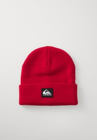 Berretto lavorato a maglia rosso con risvolto e etichetta nera quadrata con un logo di montagna bianco. Texture liscia e vestibilità aderente.