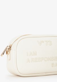 Bolsa de imitación cuero blanca con texto en relieve, herrajes de cremallera dorados, bordes redondeados y detalles de costura superior. Mide aproximadamente 20 centímetros de ancho.