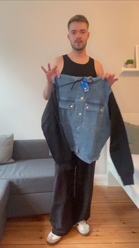 Farmerdzseki fekete ujjal, két mellzsebbel, fehér gombokkal és címkével. A test színe világoskék, ami kontrasztot képez a feketével.