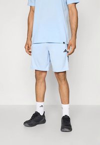 Hele sinine sportlik t-särk, millele on sobitatud samast materjalist lahtised püksid. Kaunistatud musta Adidas logo ja triipudega. Kandjaks mustad spordijalatsid ja valged sokid.