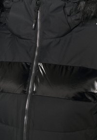 Schwarze Puffjacke mit glänzendem schwarzen Horizontalstreifen, einem durchgängigen Reißverschluss und einer abnehmbaren Kapuze mit Kunstfellbesatz. Glattes, strukturiertes Gewebe.
